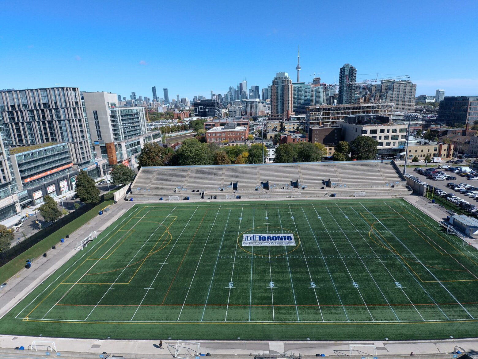 Birds eye view of soccer field with buildings and CN Tower in the background.