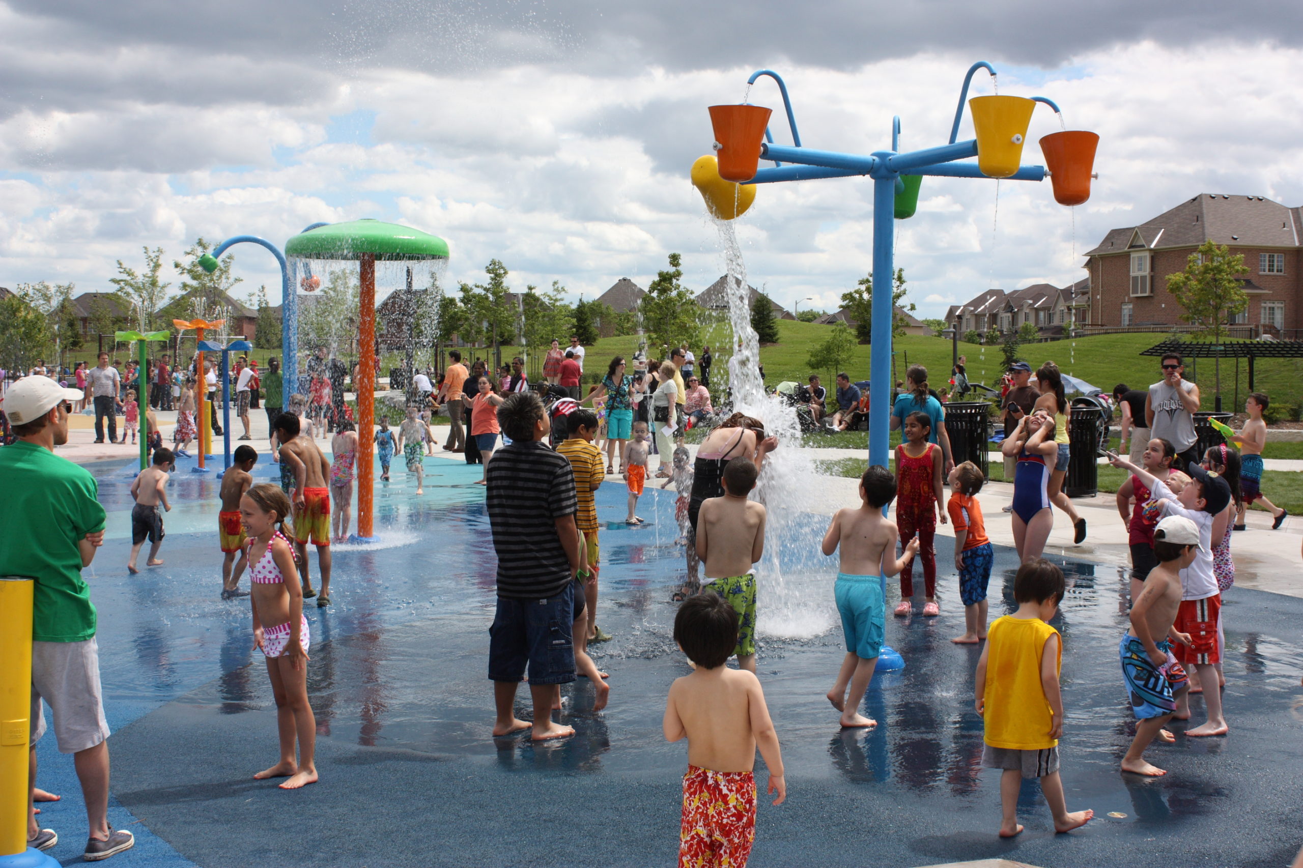 Large water park and splash pad with lots of children playing in it.