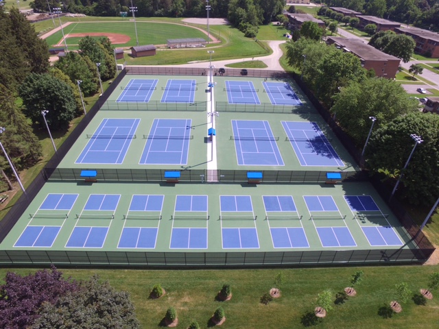 Birds eye view of multiple tennis courts.