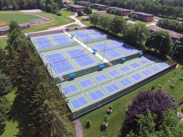 Birds eye view of multiple tennis courts.